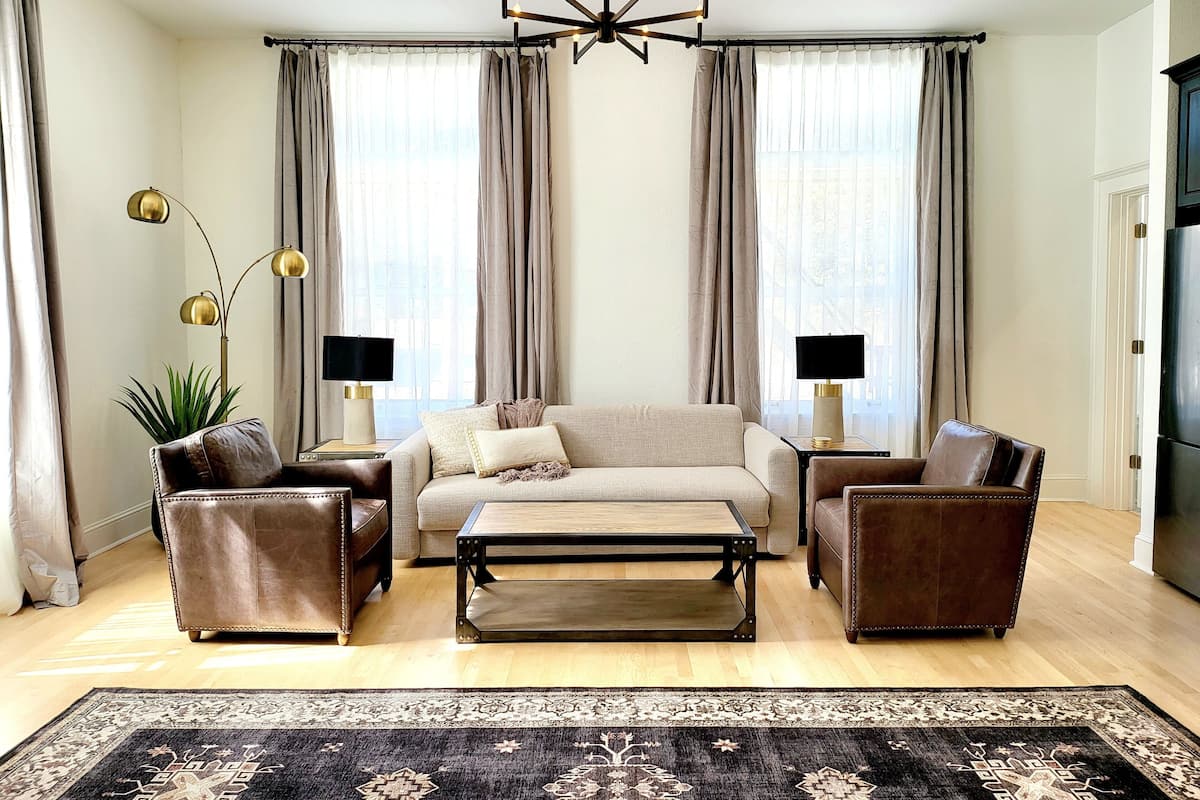 Un salon moderne avec un canapé, deux fauteuils, une table basse et un lustre.
