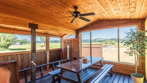 A wooden deck with picnic tables and benches, large windows offering a view of the outdoors. - Close to Coquille River, Bandon Dunes, centrally located in the county -hot tub! (Coquille)