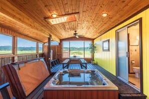 A wooden cabin with a hot tub, wooden deck, and large windows offering a view of the outdoors. - Close to Coquille River, Bandon Dunes, centrally located in the county -hot tub! (Coquille)