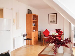 Une cuisine moderne avec des meubles blancs, un meuble en bois, une chaise noire et un coussin rouge sur un canapé.