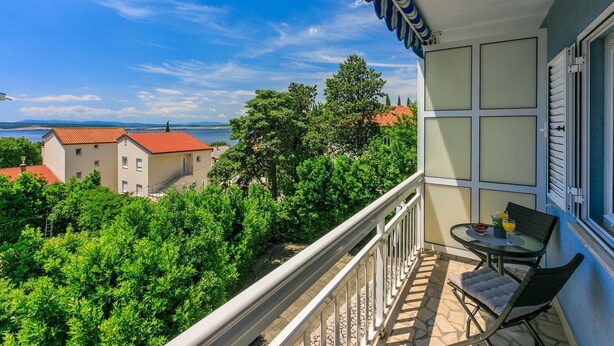 A balcony with a table and chairs, overlooking a vineyard and buildings with red roofs. - Sea view accommodation 300 metres to the beach (Dramalj)