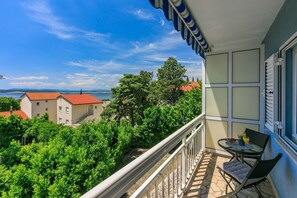 Ein Balkon mit Tisch und Stühlen, mit Blick auf einen Weinberg und Gebäude mit roten Dächern.