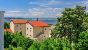 A building with a red-tiled roof, a staircase, and a view of a body of water and mountains in the background. - Sea view accommodation 300 metres to the beach (Dramalj)
