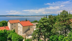 A coastal building with a red-tiled roof, surrounded by lush greenery and overlooking a calm sea. - Studio flat with sea view (Dramalj)