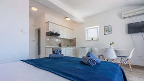A modern hotel room with a large bed, a kitchenette, a dining area, and a TV. - Studio flat with sea view (Dramalj)