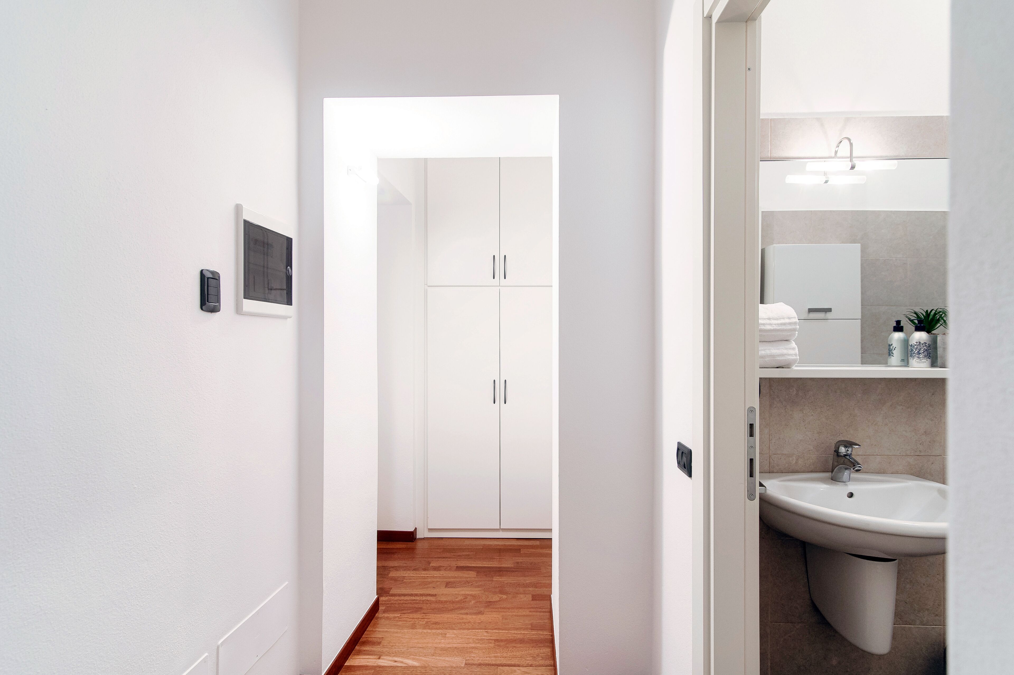 Un baño moderno con un lavamanos, espejo y muebles blancos.