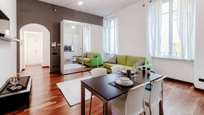 Ein modernes Wohnzimmer mit Essbereich, einem grünen Sofa und einer Küche im Hintergrund.