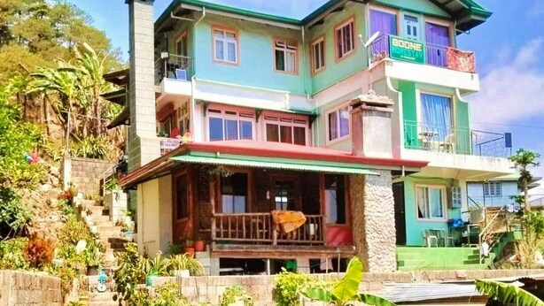 A multi-story building with a green and white facade, a balcony on the upper floor, and a staircase leading to the entrance. - FUSIONED AESTHETIC-RUSTIC RMS AT BOONE'S (Sagada)