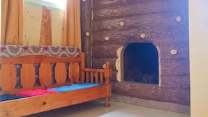A room with a wooden bed, a stone wall with a fireplace, and a window with curtains. - FUSIONED AESTHETIC-RUSTIC RMS AT BOONE'S (Sagada)