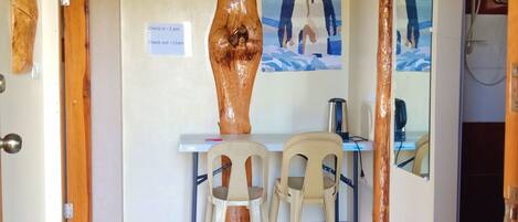 Une pièce avec un plafond en bois, une table avec deux chaises, un tableau au mur et un panneau indiquant les heures d’arrivée et de départ.