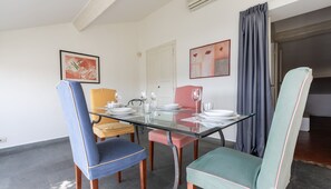 A dining area with a glass table, four chairs, and a white door.