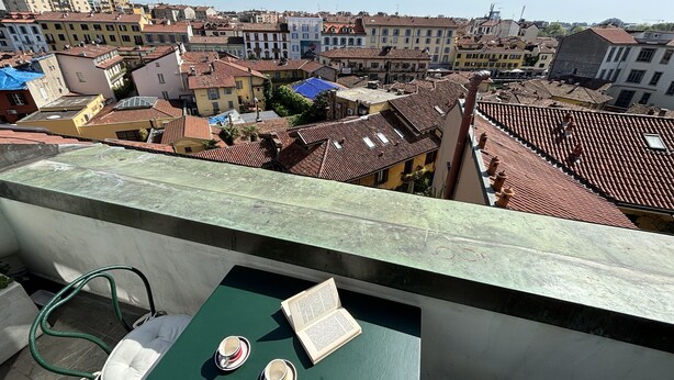 A balcony with a view of a densely packed urban area, featuring terracotta rooftops and a variety of building facades. - Italianway Comfort - Vigevano 7 (Milano)