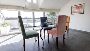 A modern room with a glass table and chairs, large windows, and a painting on the wall. - Italianway Comfort - Vigevano 7 (Milano)