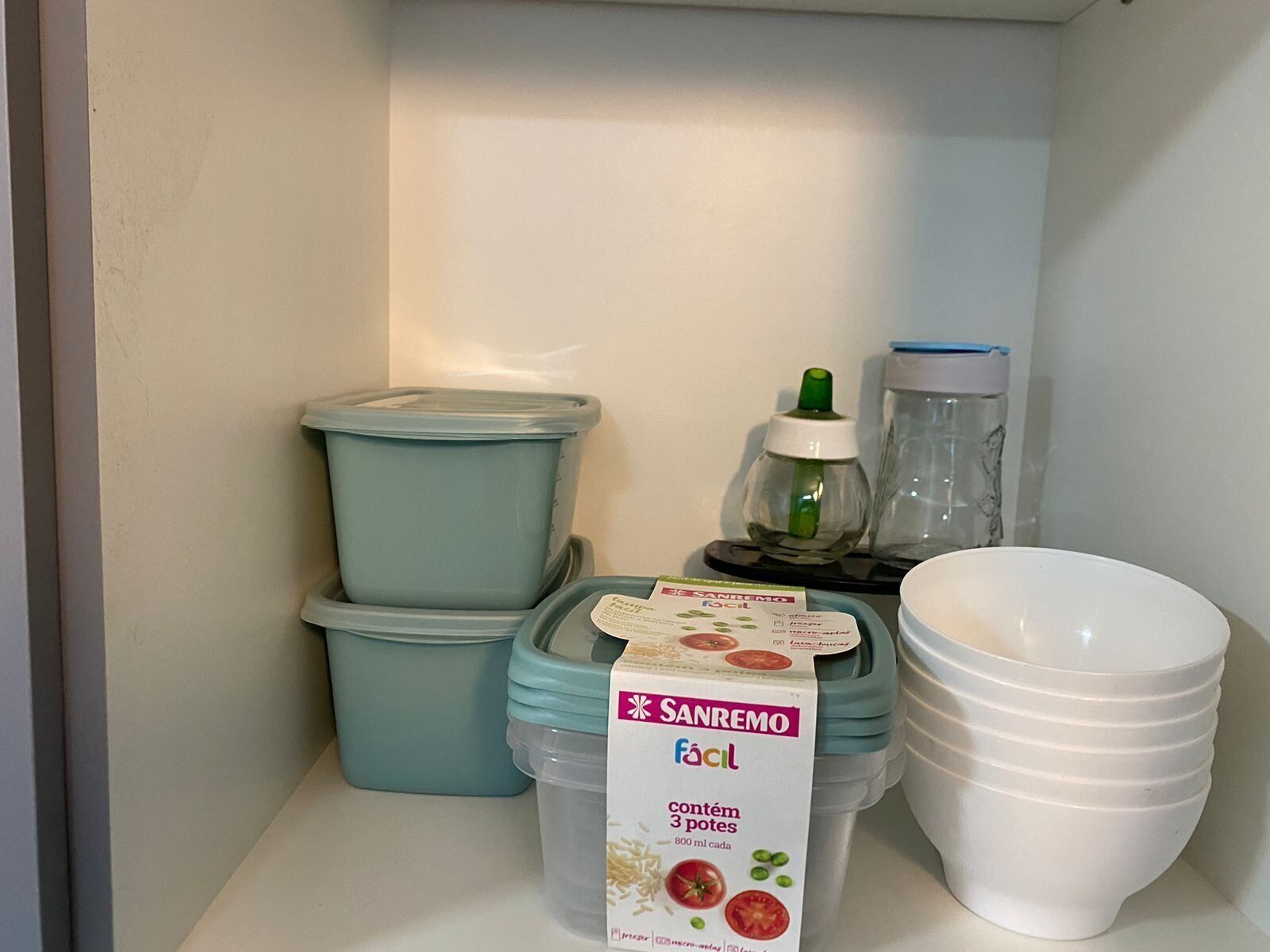 Een opslagruimte met gestapelde containers, een pak Sanremo melk en een witte kom.