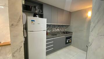 A compact kitchen with a refrigerator, a stove, and a microwave.