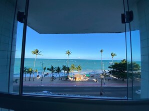 A view from a window overlooking a beach with palm trees and a clear sky. - Cote D´Azur Apto 411 (Maceió)