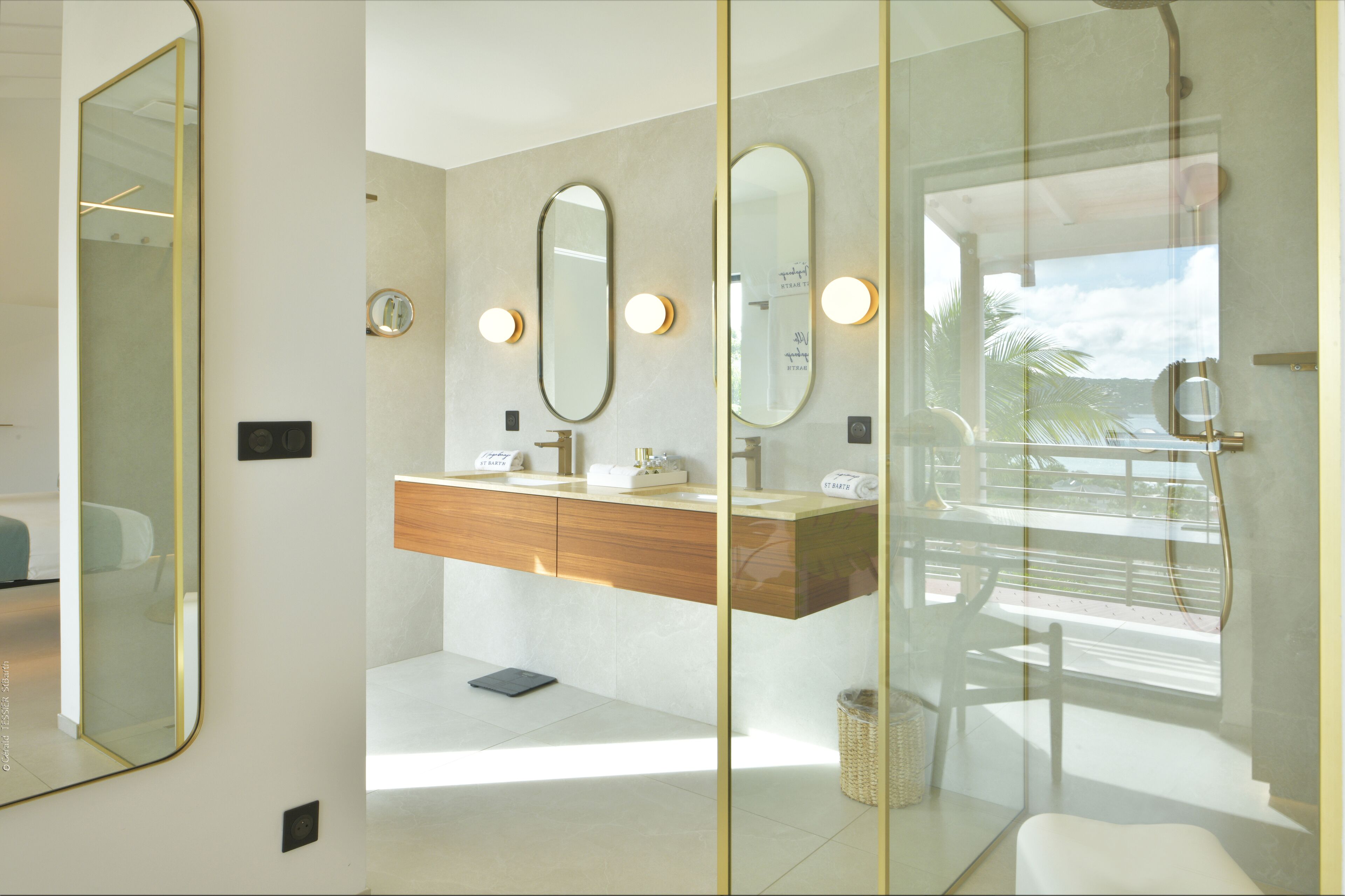Un baño moderno con cabina de ducha de vidrio, tocador de madera y un espejo grande.