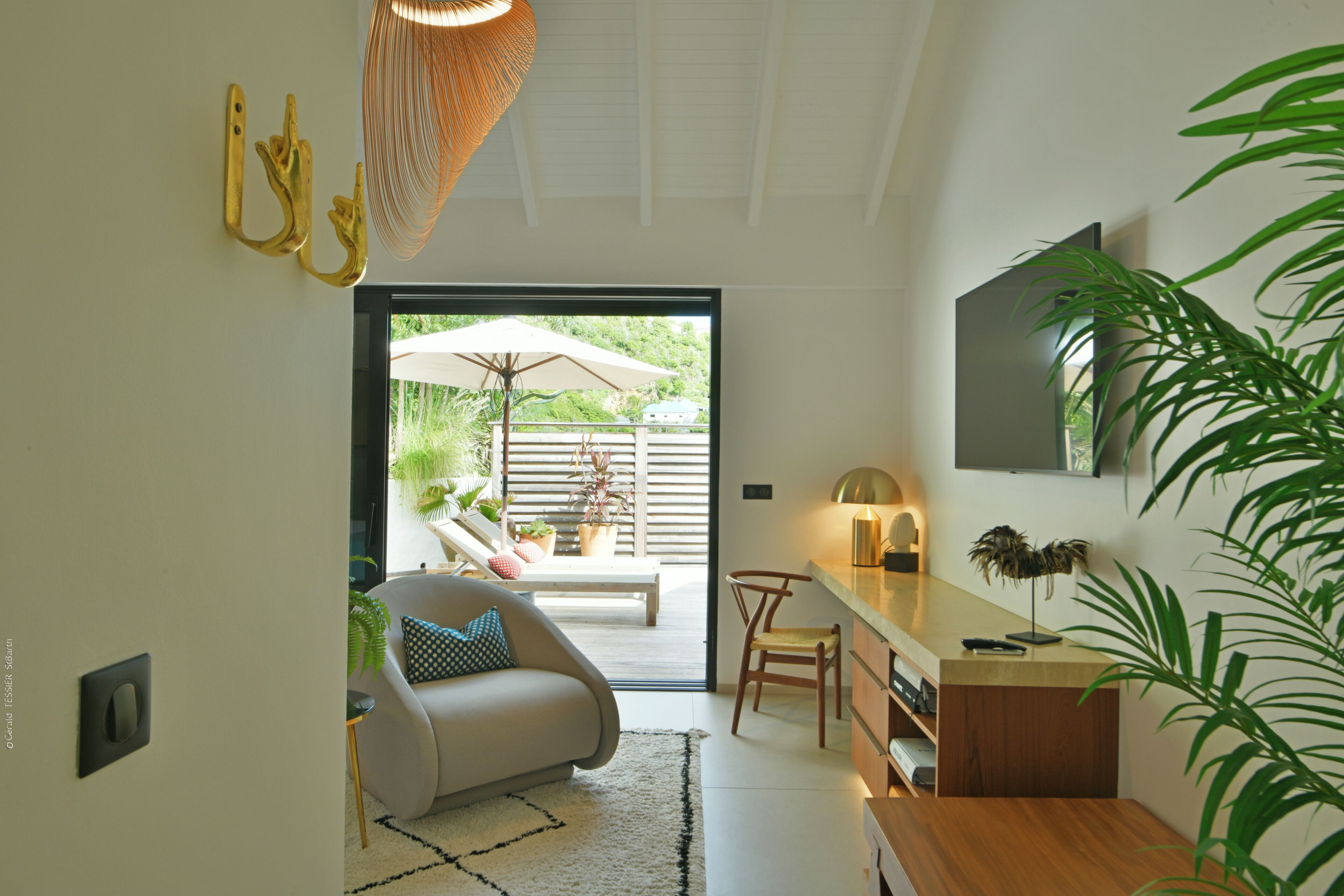 A modern interior with a sofa, a dining table, and a TV mounted on the wall.