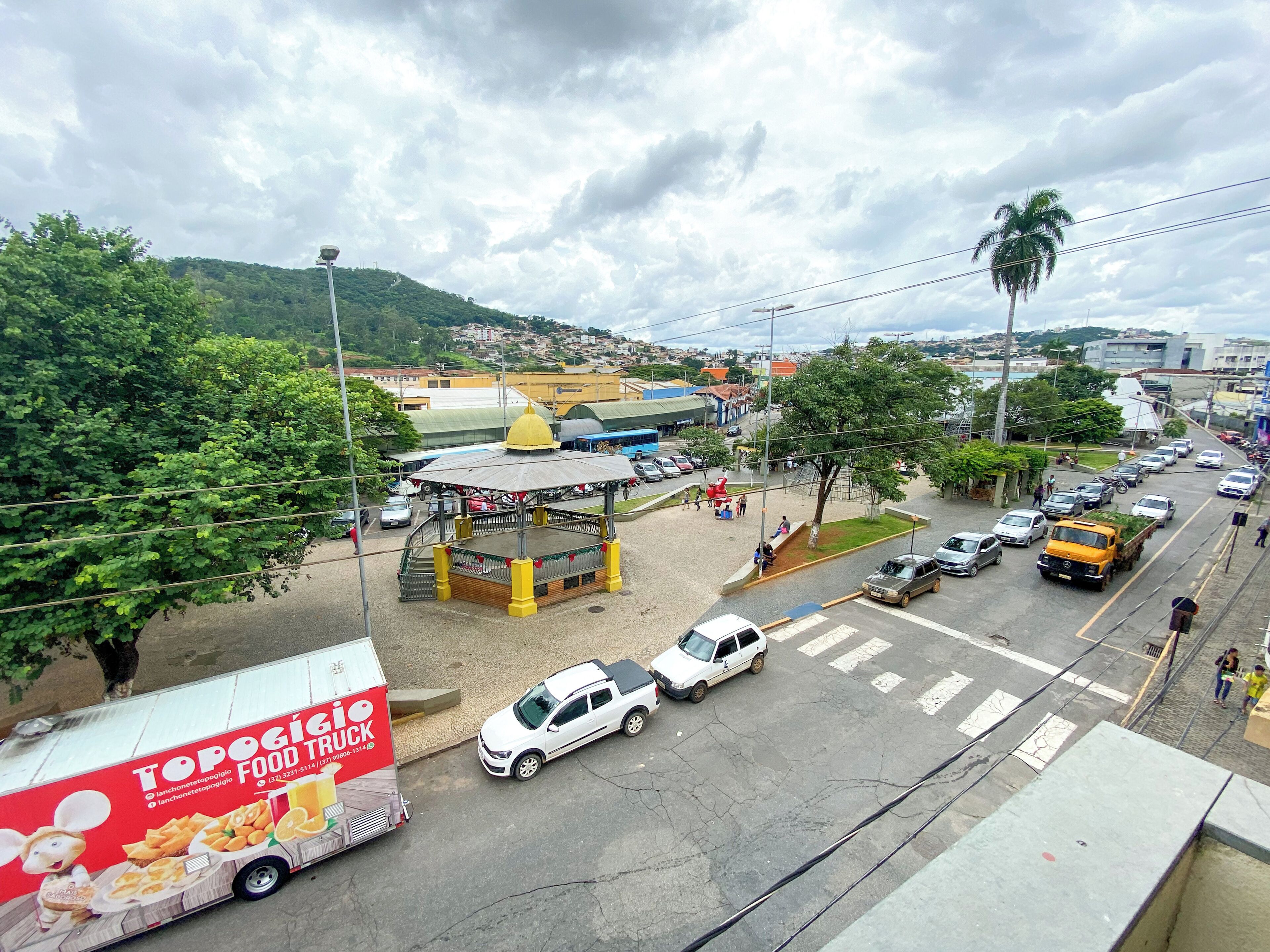 A busy street with cars, a food truck, and a gazebo.