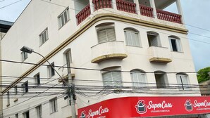 A multi-story building with a SuperCasa store on the ground floor, featuring a red awning and signage. - Elite Economy Hotel (Para de Minas)