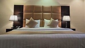 Habitación de hotel con una cama grande, dos lámparas de noche y un cabecero acolchado.