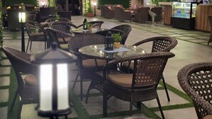 Un restaurante con sillas y mesas de mimbre, una pantalla de televisión y una pared de ladrillo.