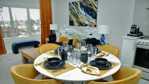 A dining area with a round table set for four, yellow chairs, and a vase of flowers. - Bright and sunny 1-bdr guest suite in South Calgary (De Winton)