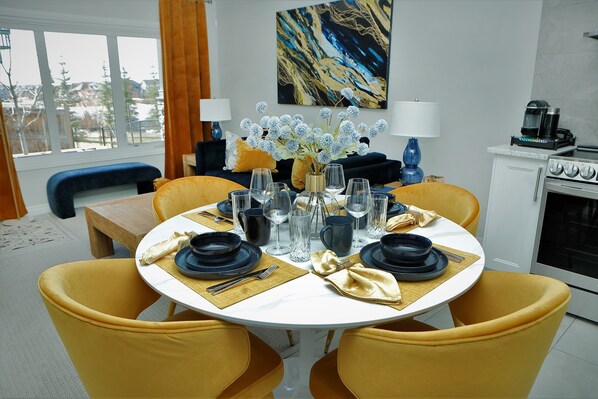 A dining area with a round table set for four, yellow chairs, and a vase of flowers.