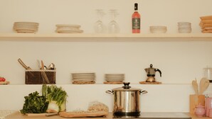 Una cucina con mensole in legno piene di piatti, ciotole e una caffettiera.