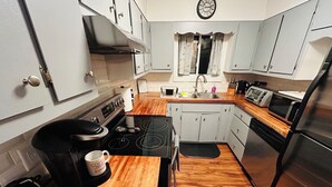 A compact kitchen with a stove, microwave, and refrigerator.