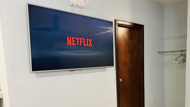 Ein Zimmer mit einem großen Flachbildfernseher an der Wand, der das Netflix-Logo zeigt.