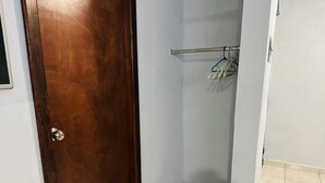 Ein schmaler Flur mit einer Holztür, einem Kleiderständer mit Kleiderbügeln und einem gefliesten Boden.