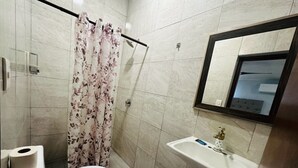 Ein Badezimmer mit Toilette, Waschbecken, Dusche mit Blumenmuster und Spiegel.