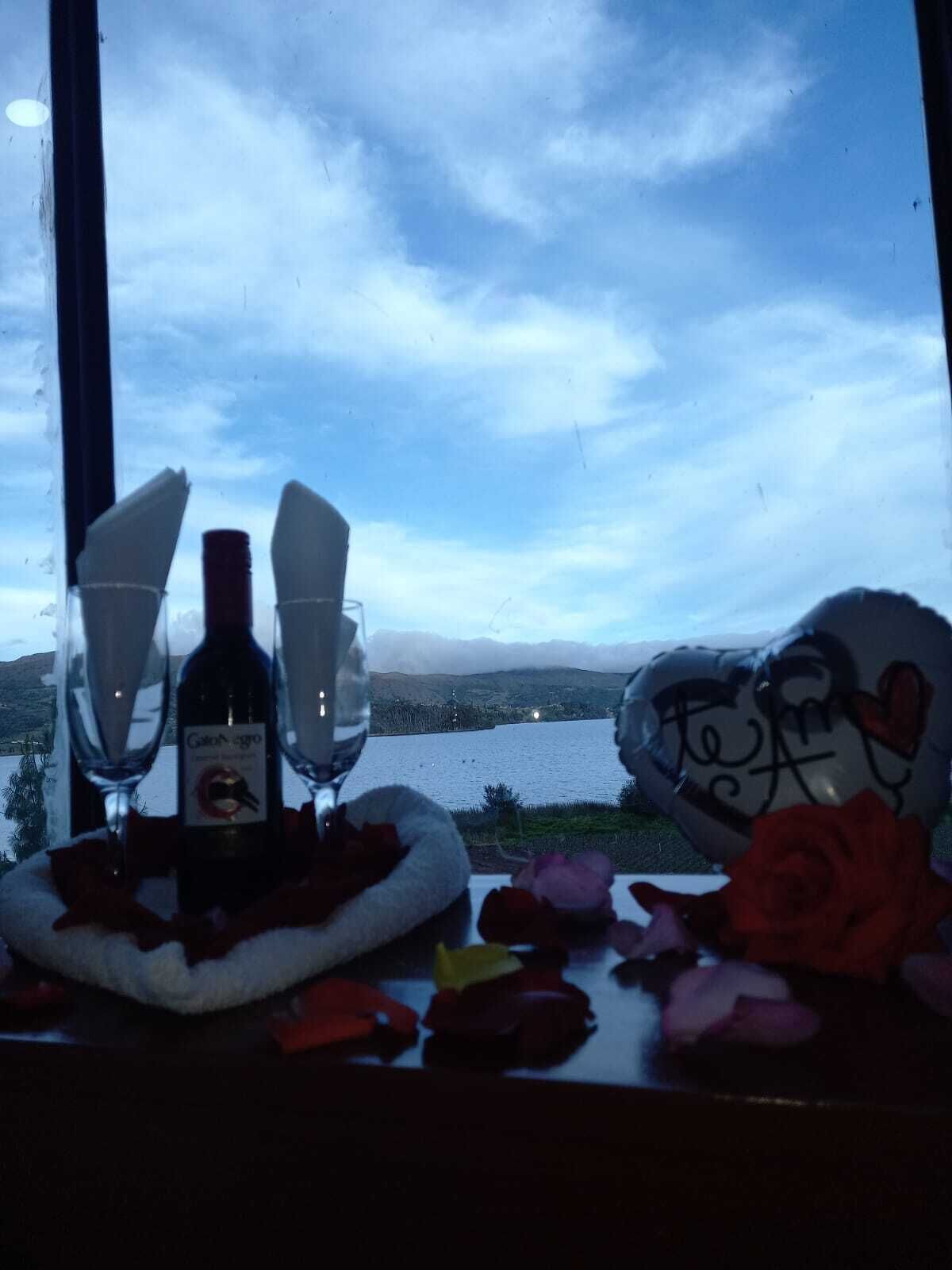 Ein Tisch mit einer Weinflasche, zwei Gläsern und einem Kuscheltier mit Herz.