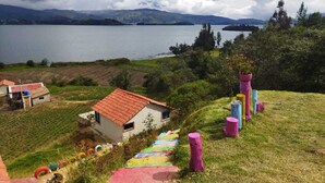 A rural landscape with a small house, colorful painted steps, and a lake in the background.
