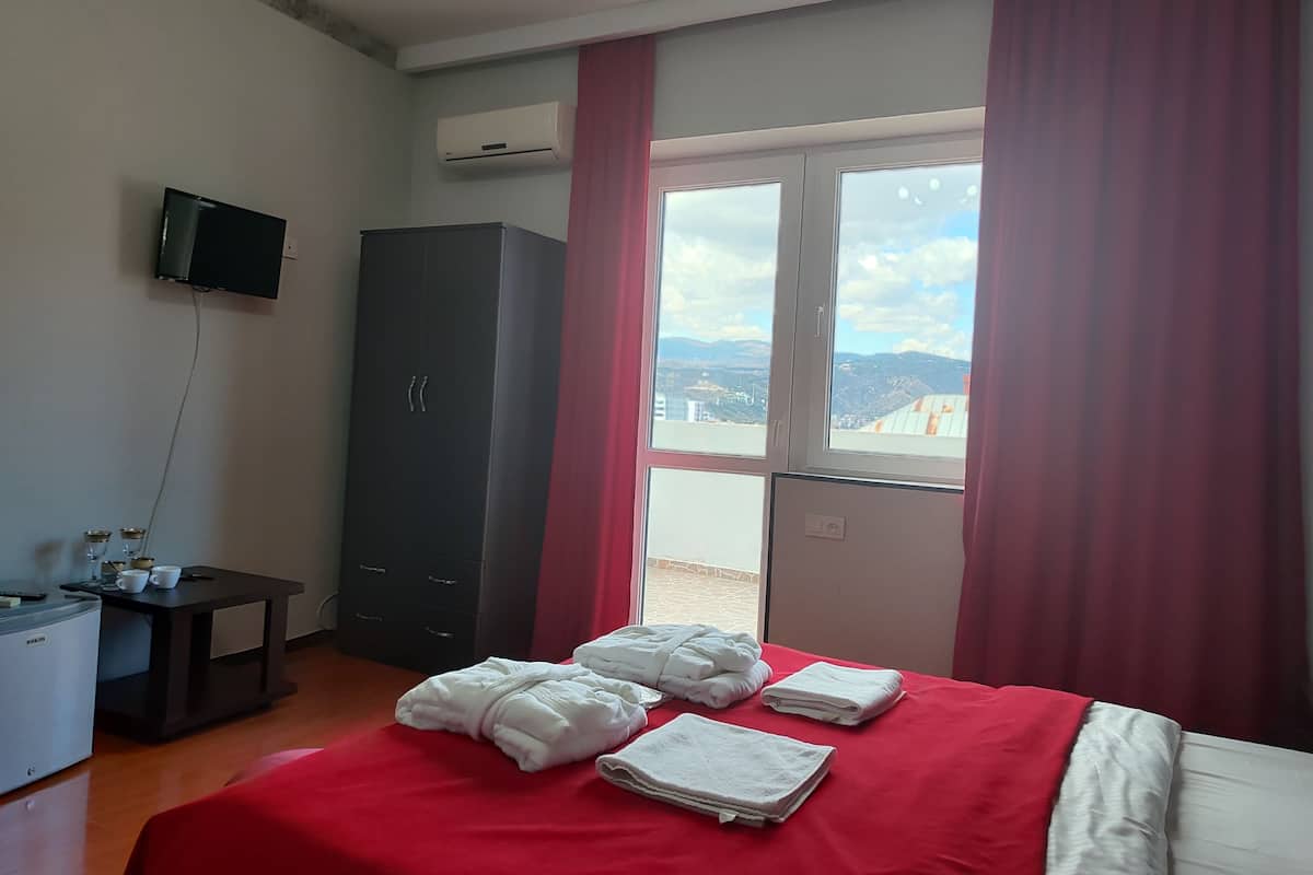 Una habitación de hotel con cama, escritorio, armario y televisor.