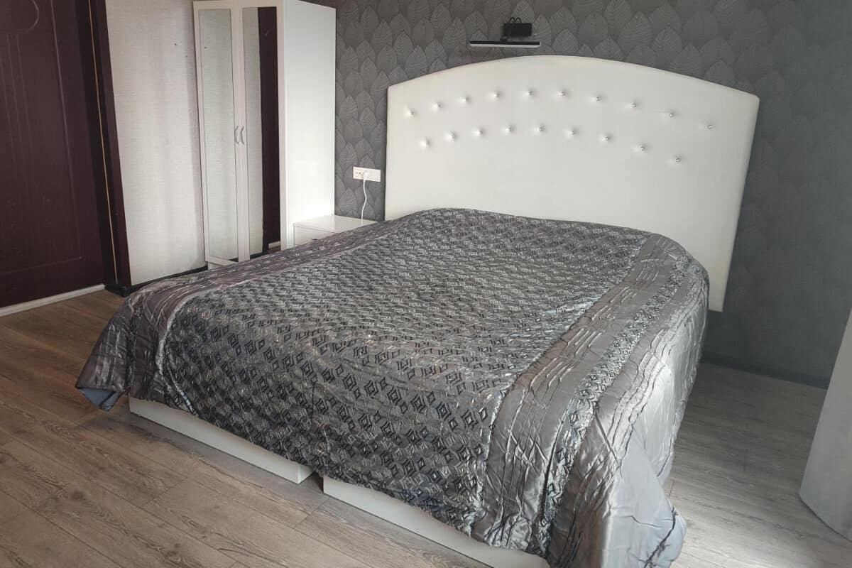 Un dormitorio con cama, armario y mesita de noche.