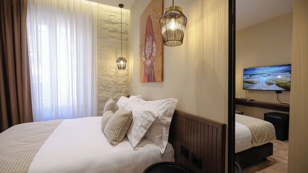 Une chambre d’hôtel avec un grand lit, une table de chevet, un miroir et un téléviseur.
