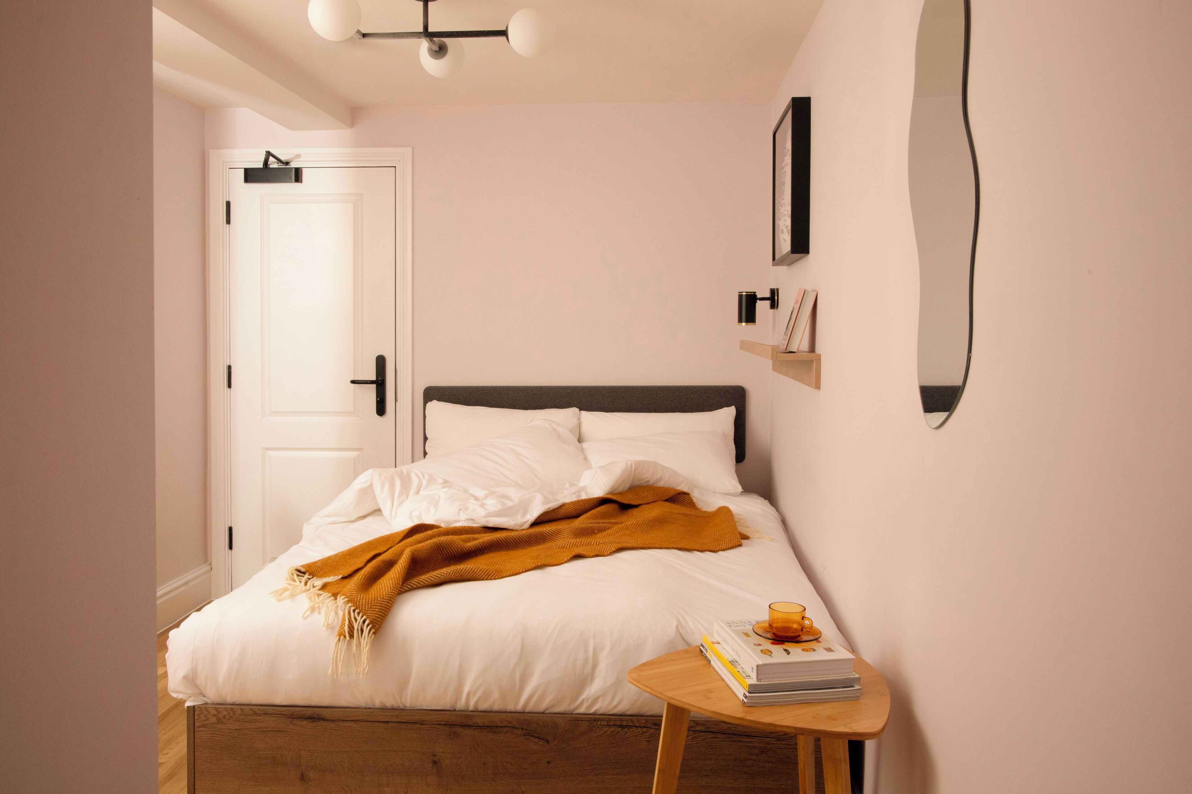 A bedroom with a bed, bedside table, and a door.