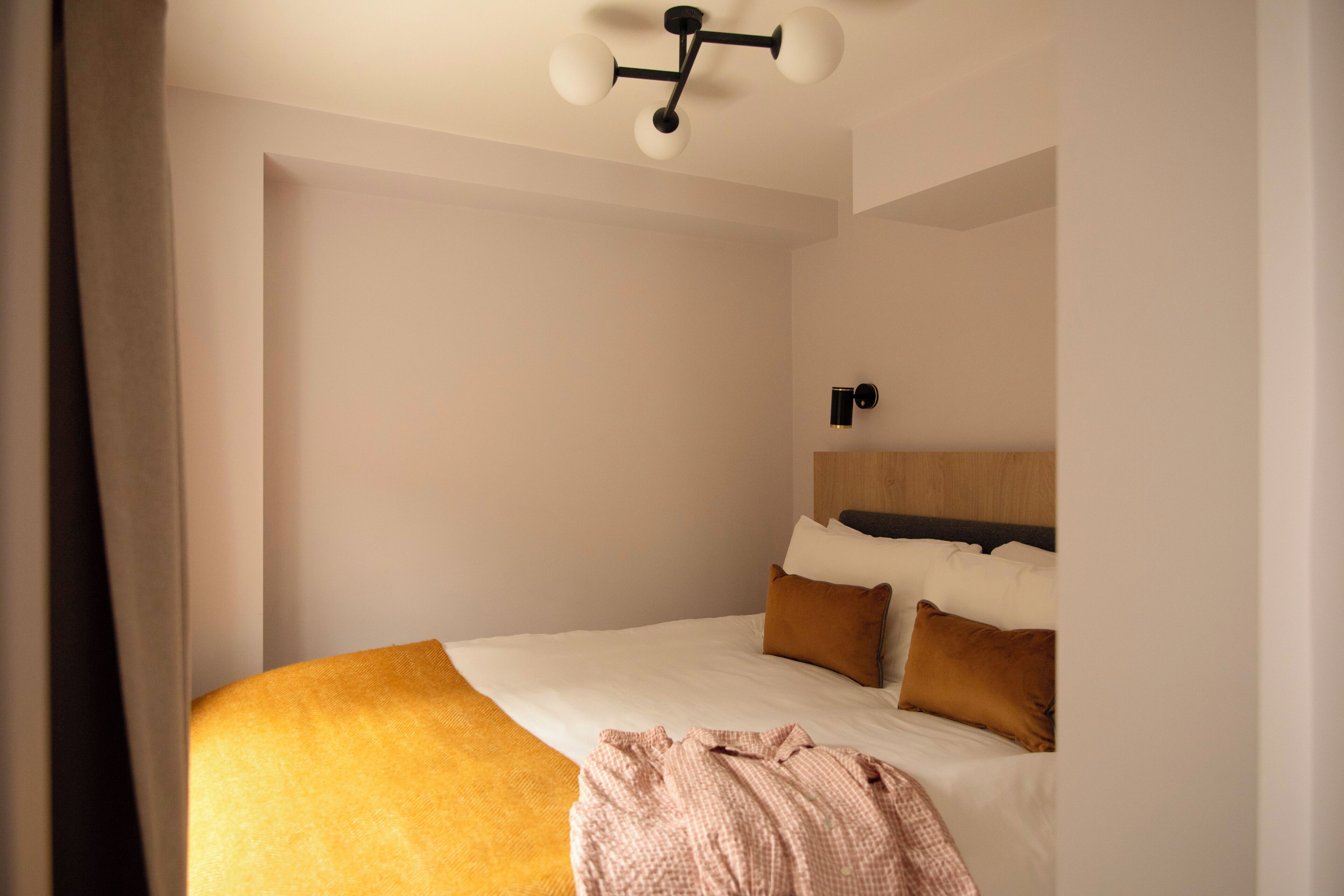 A bedroom with a bed, a headboard, and a ceiling light fixture.