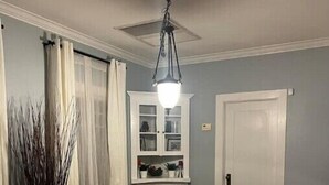 A dining area with a wooden table, white chairs, a chandelier, and a cabinet with glass doors. - Spacious & Inviting Bungalow near Downtown
 (Phoenix)