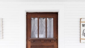Una puerta de madera con un panel de vidrio esmerilado y un felpudo que dice 'enjoy today'.