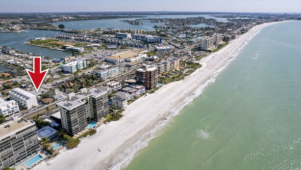 Vista aérea de una ciudad costera con playa, edificios y un puerto deportivo.