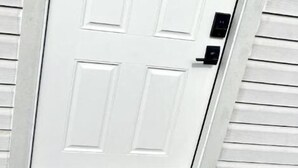A white door with a rectangular panel design, a keyhole, and a small electronic lock. - Exclusive Loft (San Antonio)