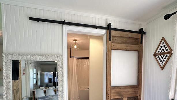A room with a mirrored sliding door, a wooden sliding barn door, and a dining area with a blue sofa and chairs. - D'Arbonne Nest Rentals: The Gator's Nest (Union Parish)