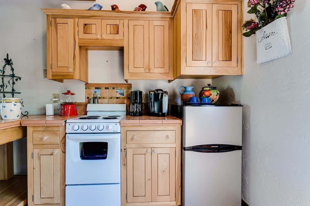 A kitchen with wooden cabinets, a stove, a refrigerator, and various kitchen appliances.
