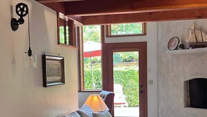A living room with a sofa, a fireplace, and a view through a door. - Charming Italian Villa Retreat • 10 Min to UO & Autzen (Eugene)