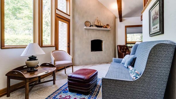A cozy living room with a fireplace, a sofa, a chair, and a table with a lamp. - Charming Italian Villa Retreat • 10 Min to UO & Autzen (Eugene)