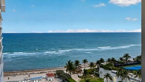 Vista costera con playa, palmeras y una vía de tren.