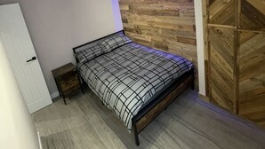 Une chambre à coucher comprenant un lit, une table de chevet, une armoire et un mur orné de panneaux en bois.